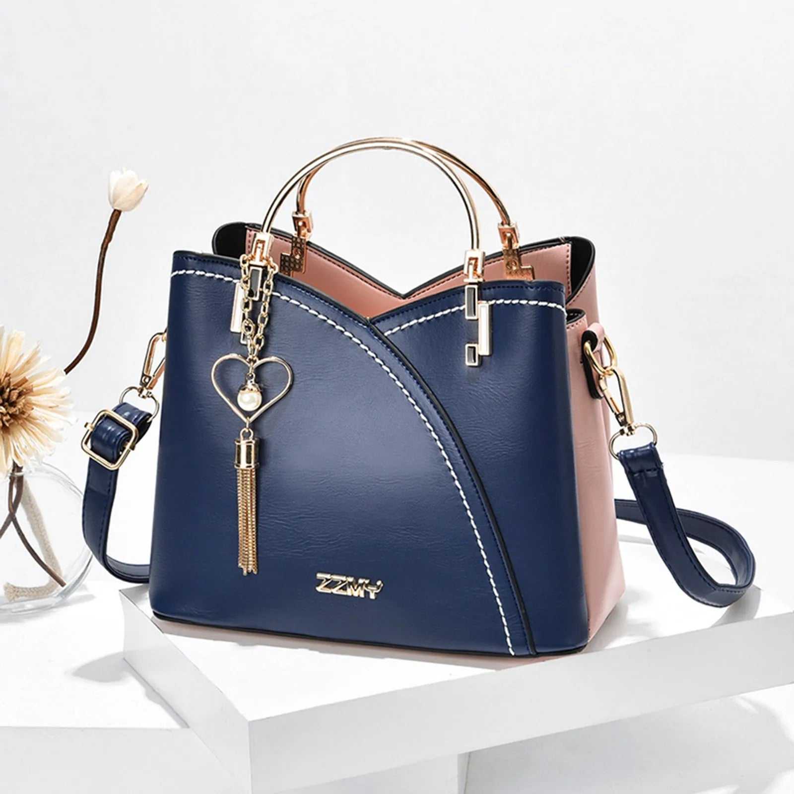 Stylish blue and pink women's handbag with heart charm, versatile design for shoulder and crossbody wear, large capacity.