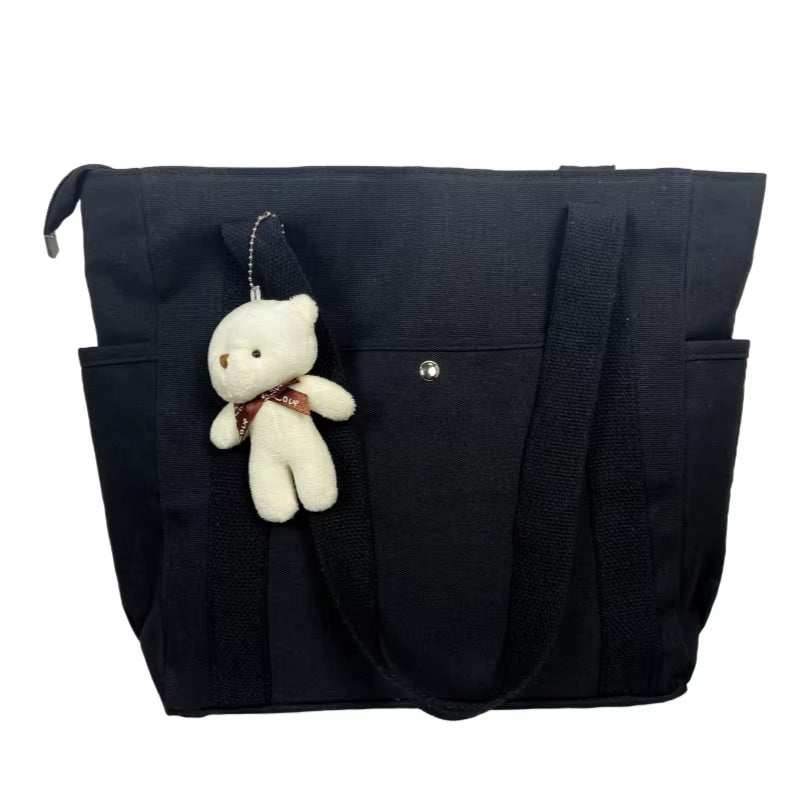 Large black canvas shoulder bag with teddy bear accessory, ideal for work and commuting.