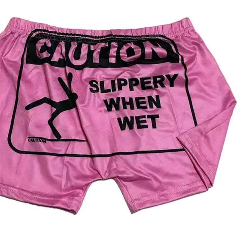 Soft pink pajama boxer bottoms with "Caution Slippery When Wet" graphic design, perfect for lounging.