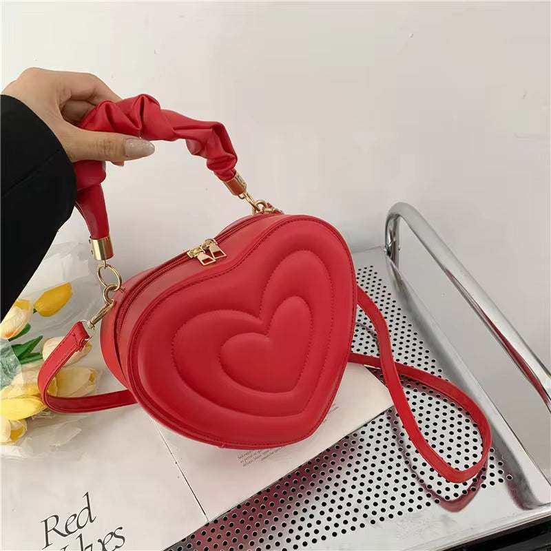 Fashion love heart shape red shoulder bag in premium PU leather with top handle and crossbody strap.