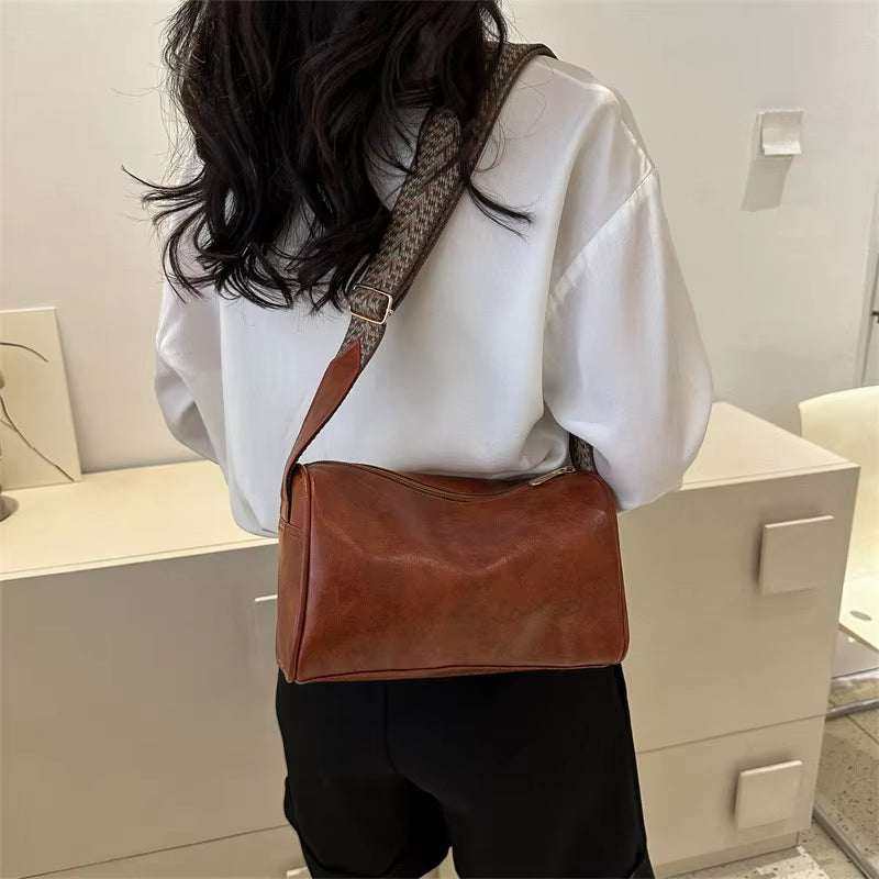 Vintage leather Boston women's crossbody bag in brown, worn by a model for stylish accessory appeal.