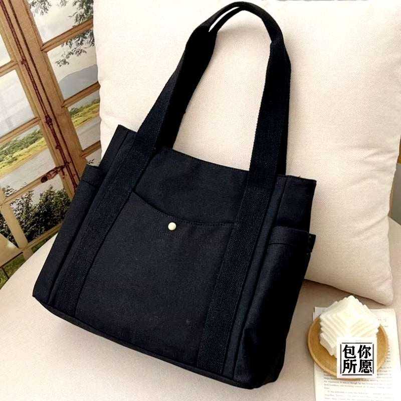 Large black canvas shoulder bag with sturdy straps, ideal for work and commuting.