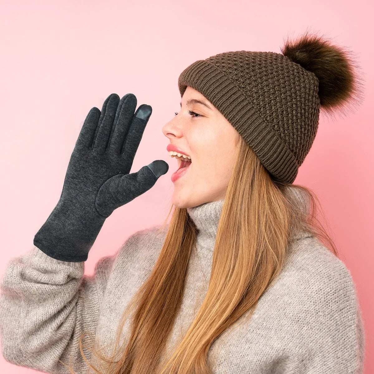 Woman wearing brown knitted hat, gray sweater, and Fingers Gloves with touchscreen fingertips on pink background.