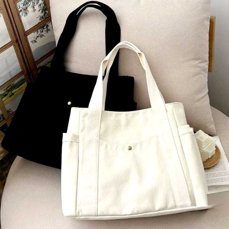 Large canvas shoulder bag for commuting and work, available in black and white.