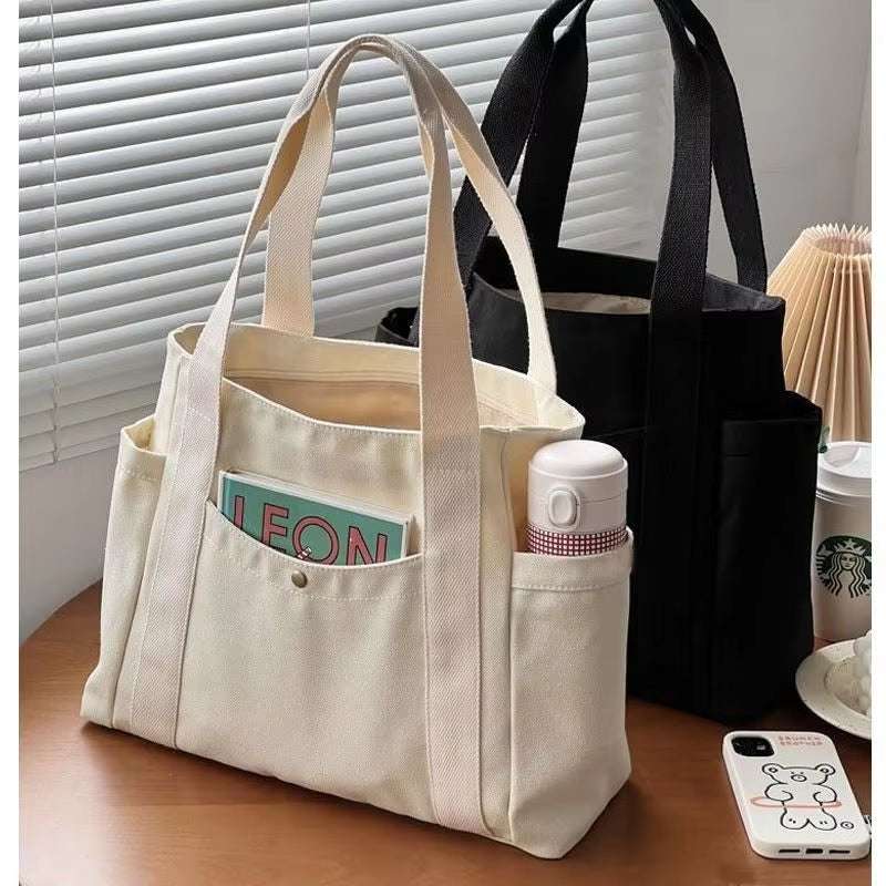 Large canvas shoulder bag for work and commuting, spacious and durable design.