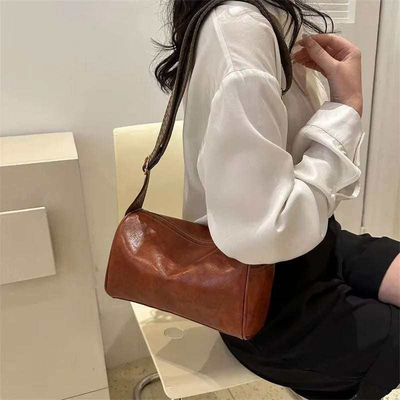Vintage leather Boston crossbody bag for women on a white surface.