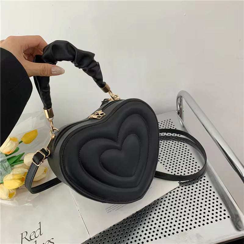 Heart-shaped PU leather shoulder bag with top handle and crossbody option.