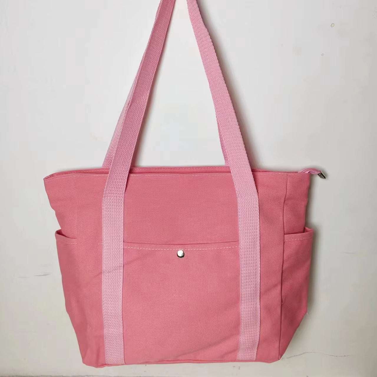 Large canvas shoulder bag in pink with long straps, perfect for work and commuting.