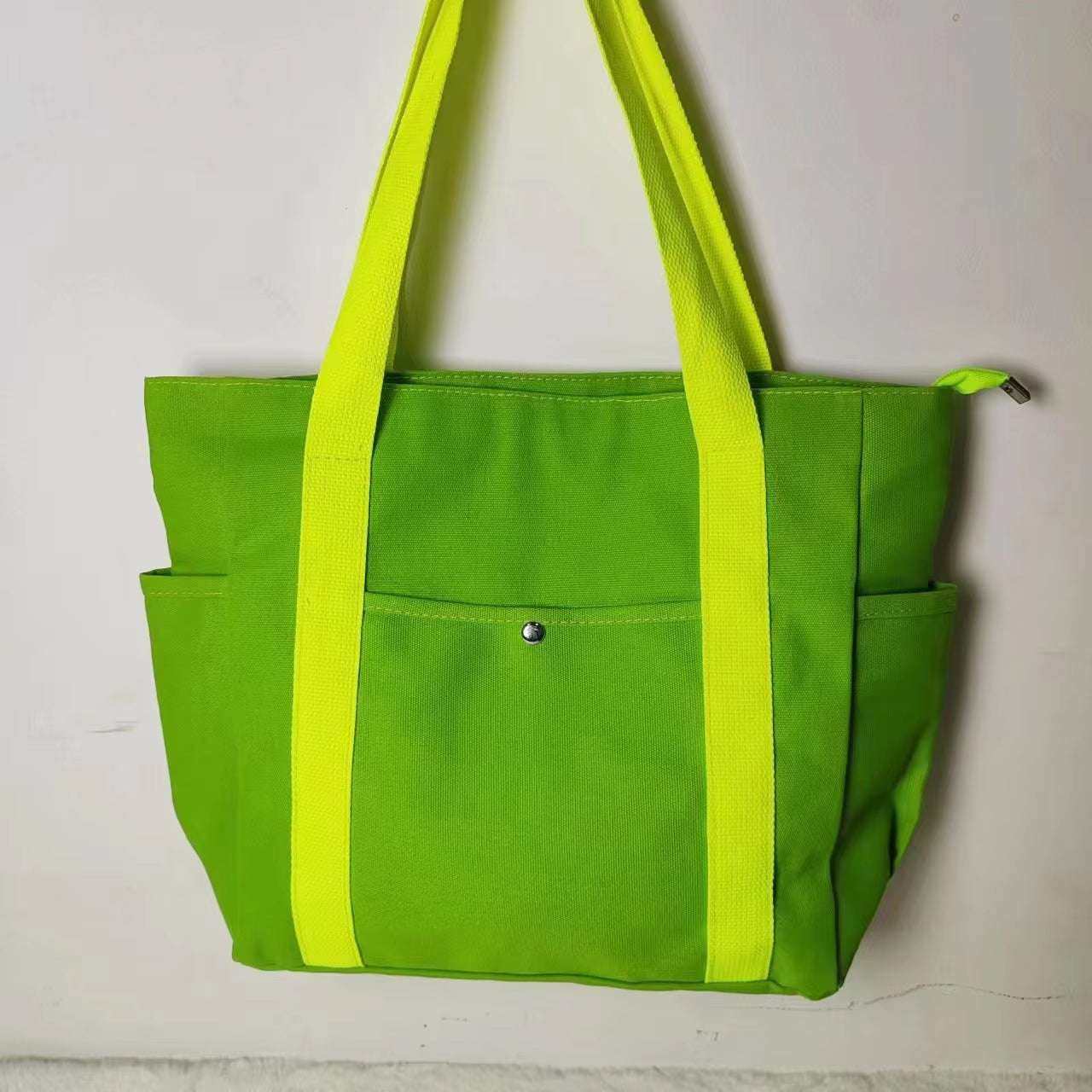 Large green canvas shoulder bag with yellow straps, perfect for work or commuting.