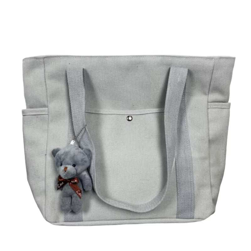Large canvas shoulder bag with teddy bear charm, ideal for work and commuting.