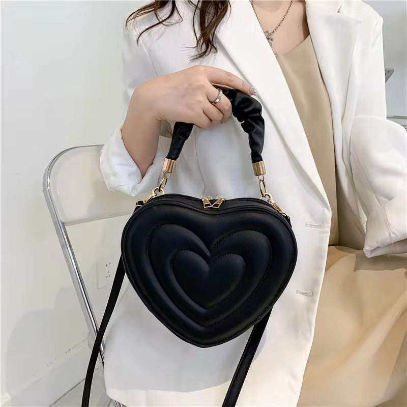 Heart-shaped black shoulder bag with top handle and crossbody strap made from PU leather, perfect for women's fashion.